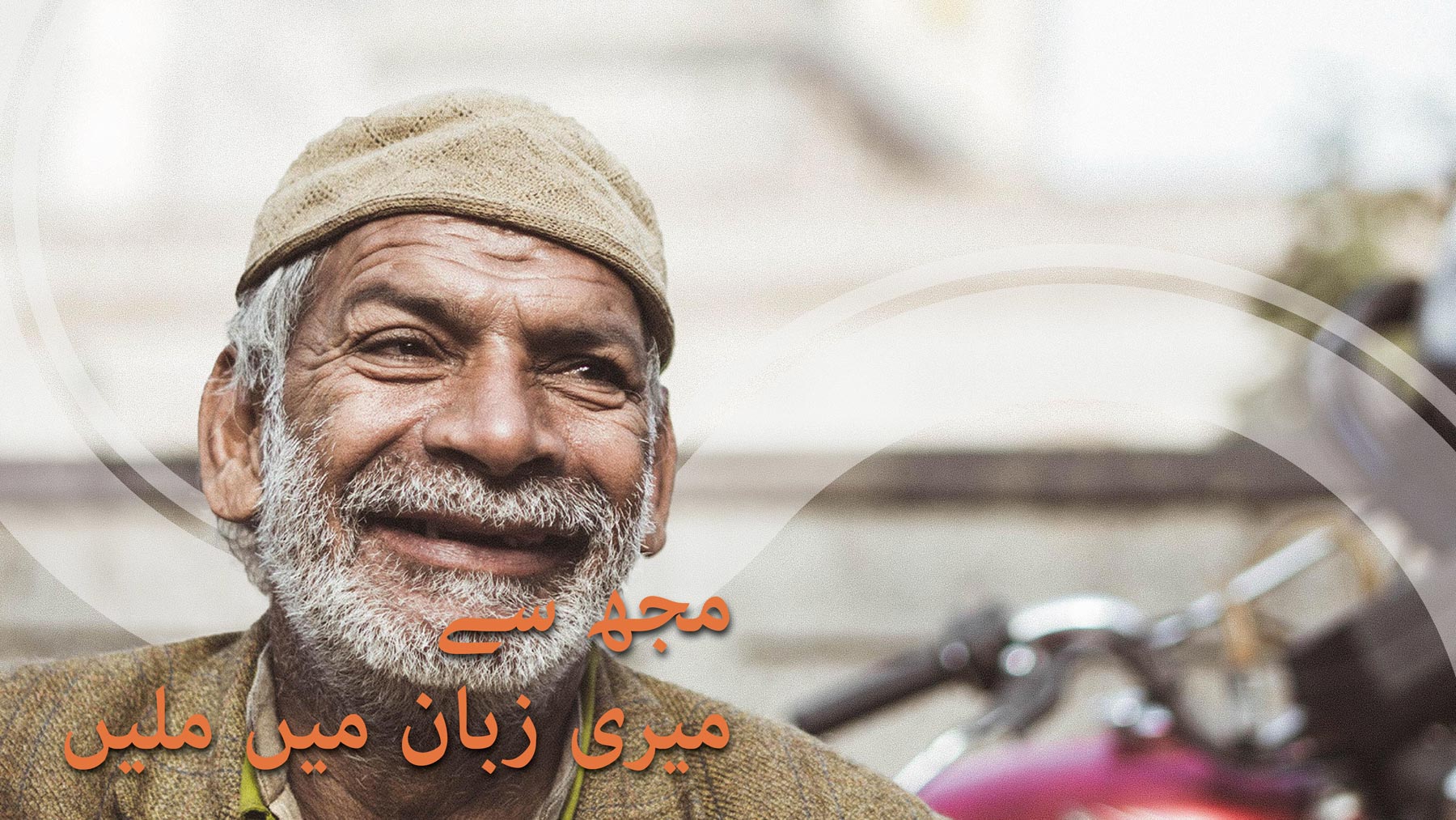 Man with grey beard smiling and Arabic text