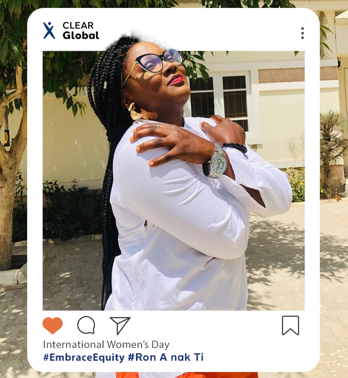 CLEAR Global team member Joy poses with her arms crossed for International Womens Day. She stands outdoors in Nigeria, facing left with her eyes closed and red lipstick smiling, in a crisp white shirt. There is a white instagram frame surrounding her with the caption reading International Womens Day #EmbraceEquity