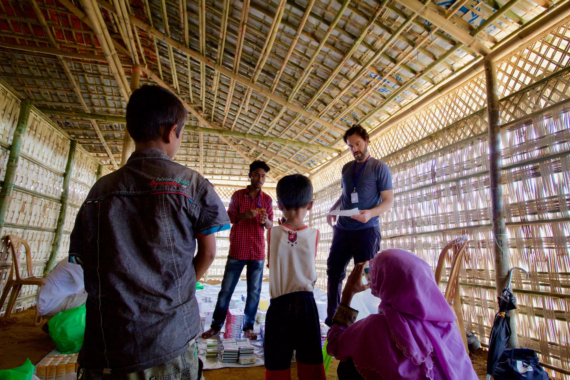 Rohingya Interpreter (center) works with a doctor (back right) to explain medication dosage instructions at a new medical facility in Kutupalong makeshift camp near Cox's Bazar, Bangladesh. Photo_ Eric Deluca _ TWB