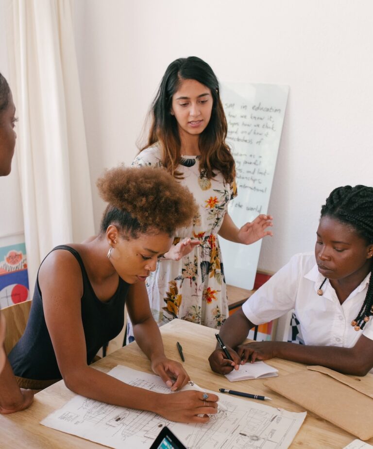 Three women working, with a whiteboard behind them