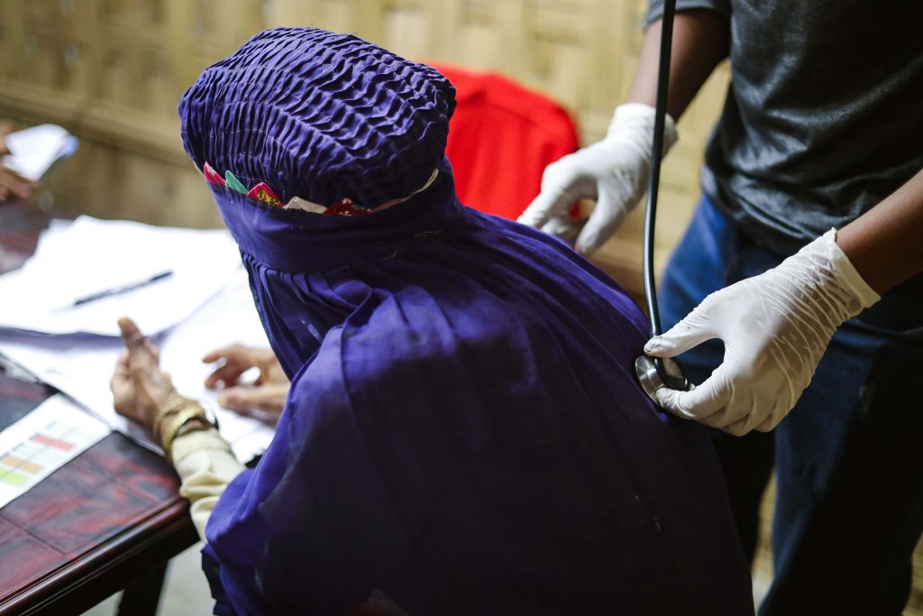 Rohingya woman wearing purple has a check up with a doctor