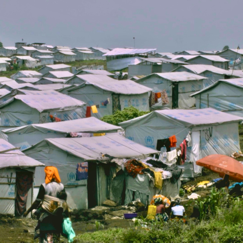 Kanyaruchinya camp, shelters, and a woman walking in the distance - women's rights blog