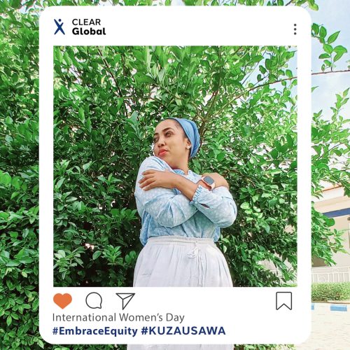 Photo of CLEAR Global team member Hadija in Kenya. She is standing outside in front of trees wearing white bottoms, a blue top and headscarf, standing with her arms crossed to signify "embrace equity". An instagram frame surrounds her with the text "International women's day and #EmbraceEquity" in English and Swahili