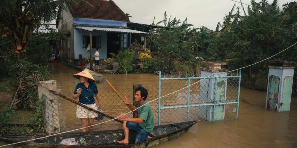 Residents navigate floodwaters in Phú Yên, Vietnam, using a small wooden boat.
