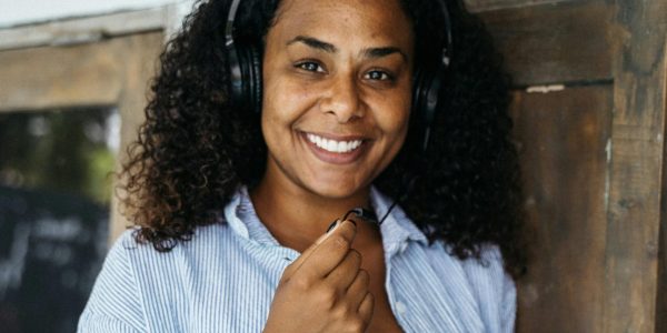 Photograph Of A Woman With Headphones Holding Her Laptop Computer